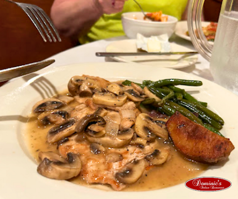 Plate with sautéed mushrooms, green beans, and a piece of fried fish, with a slice of lemon and a fork on the side.