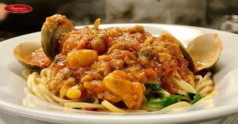 Spaghetti pasta topped with seafood marinara sauce and clams. Mildly garnished with green herbs.