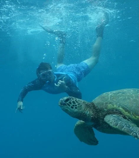 Person swimming underwater next to a sea turtle.
