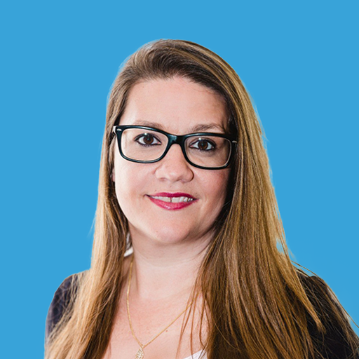 Portrait of a woman with long straight hair and glasses, smiling against a blue background.