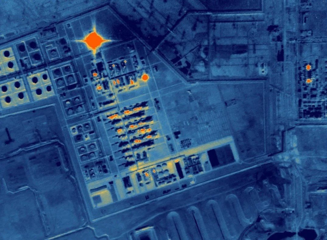 Thermal image of an industrial complex at night with bright heat signatures