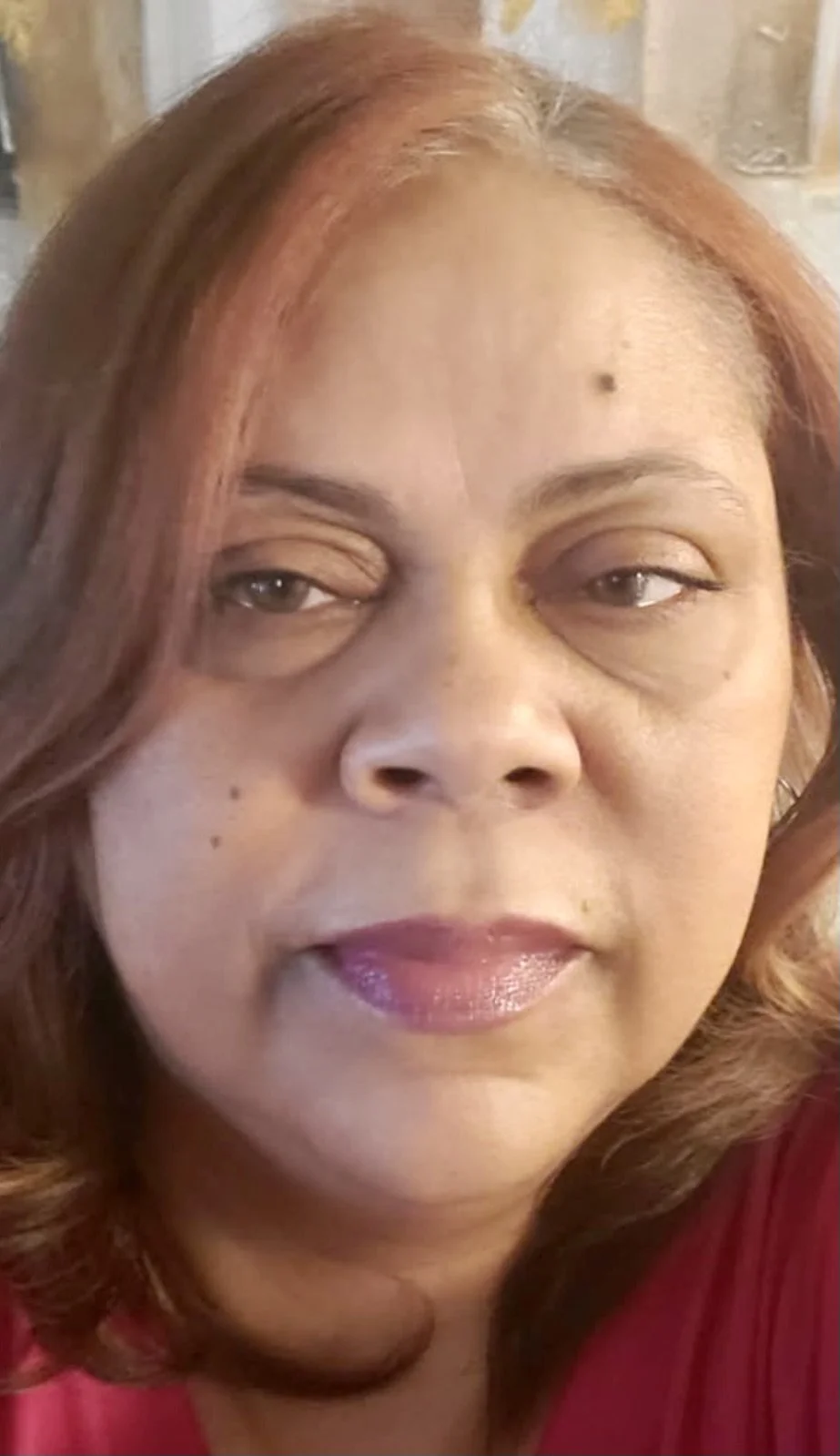 A close-up of a woman with brown hair and neutral expression.