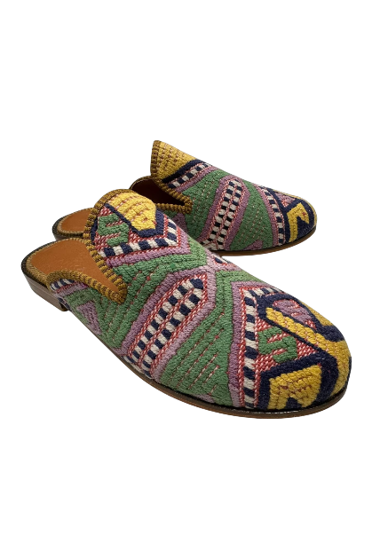 Colorful embroidered slippers with geometric and floral patterns, brown leather detailing, and a black sole.