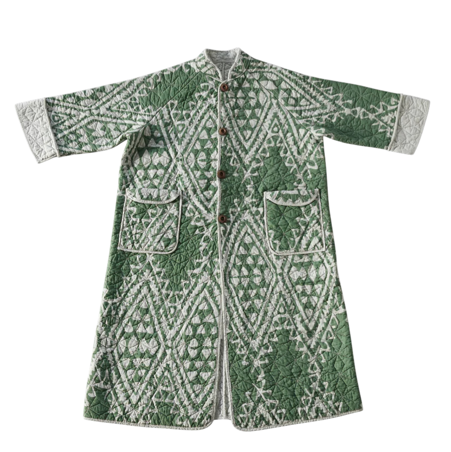 A quilted dress with a green and white geometric pattern, button closure, and two front pockets.