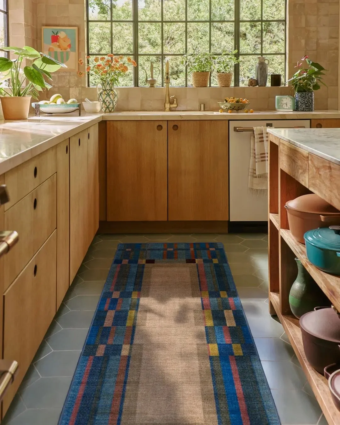 Everything is coming into frame. The Lad Blue Rug pairs a structured wide plaid border of royal blue, warm pink, deep navy, umber, rich deep orange, and warm neutrals with pops of yellow against an open neutral field, translated from Justina Blakeney