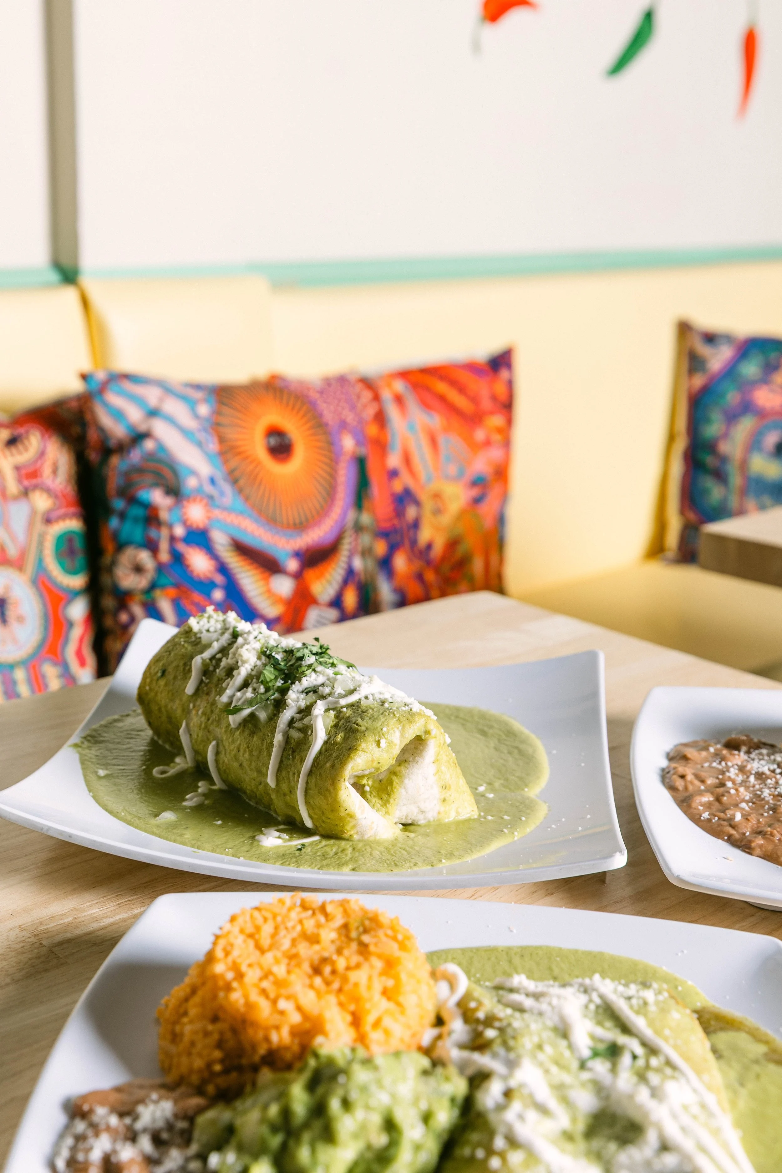 Delicious wet burrito topped with green salsa, melted cheese, and fresh toppings at Poblano Pepper Restaurant in Portland, Oregon.