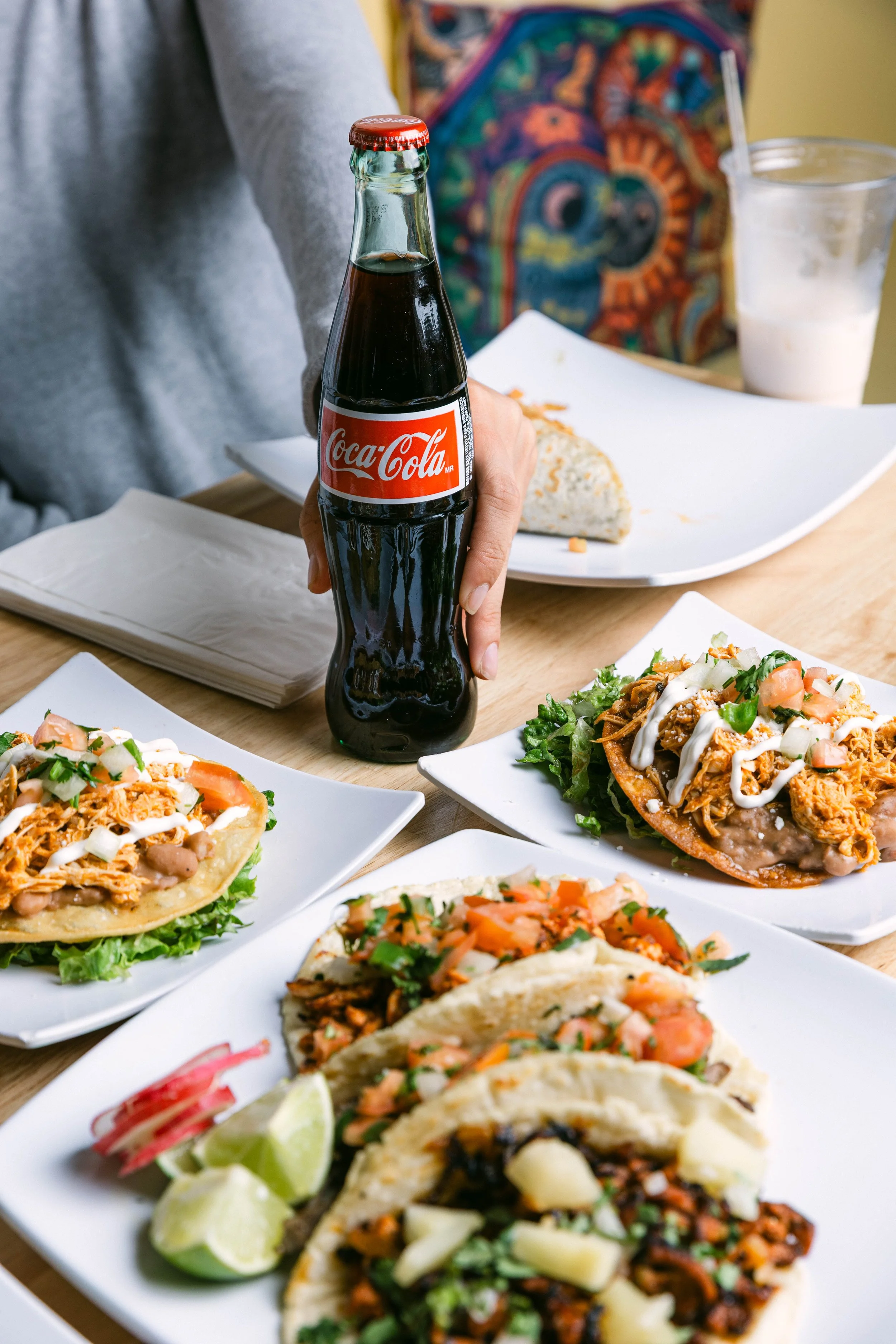 Coke bottle being held at Poblano Pepper PDX Restaurant with tacos, burritos and tostadas