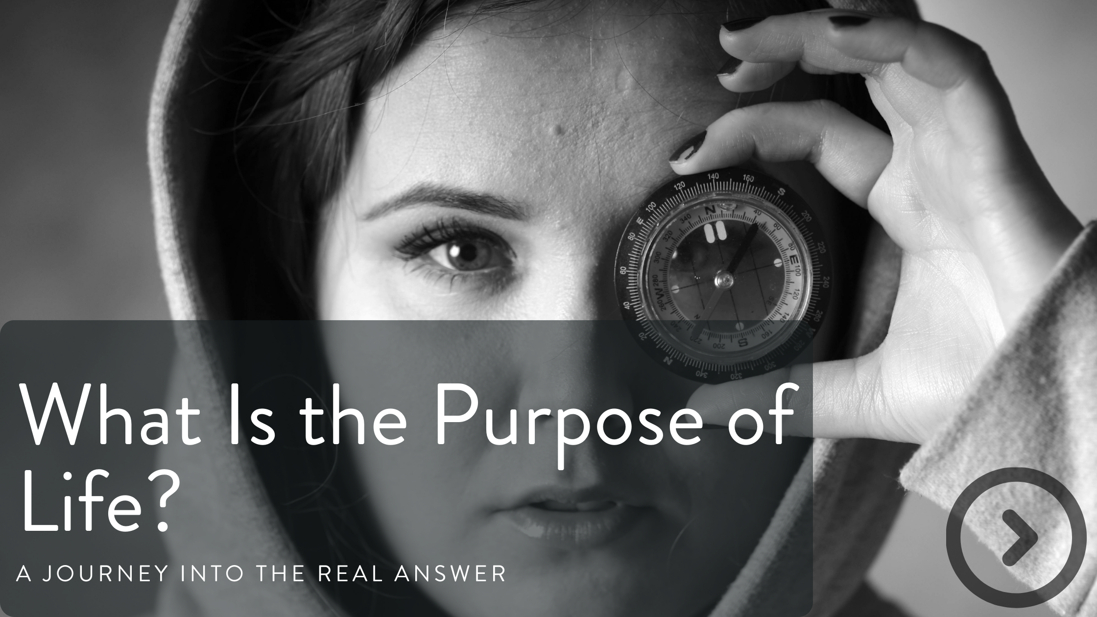 A woman with one eye visible holds a compass up to her face. She is wearing a hoodie and has dark nail polish. The image is in black and white.