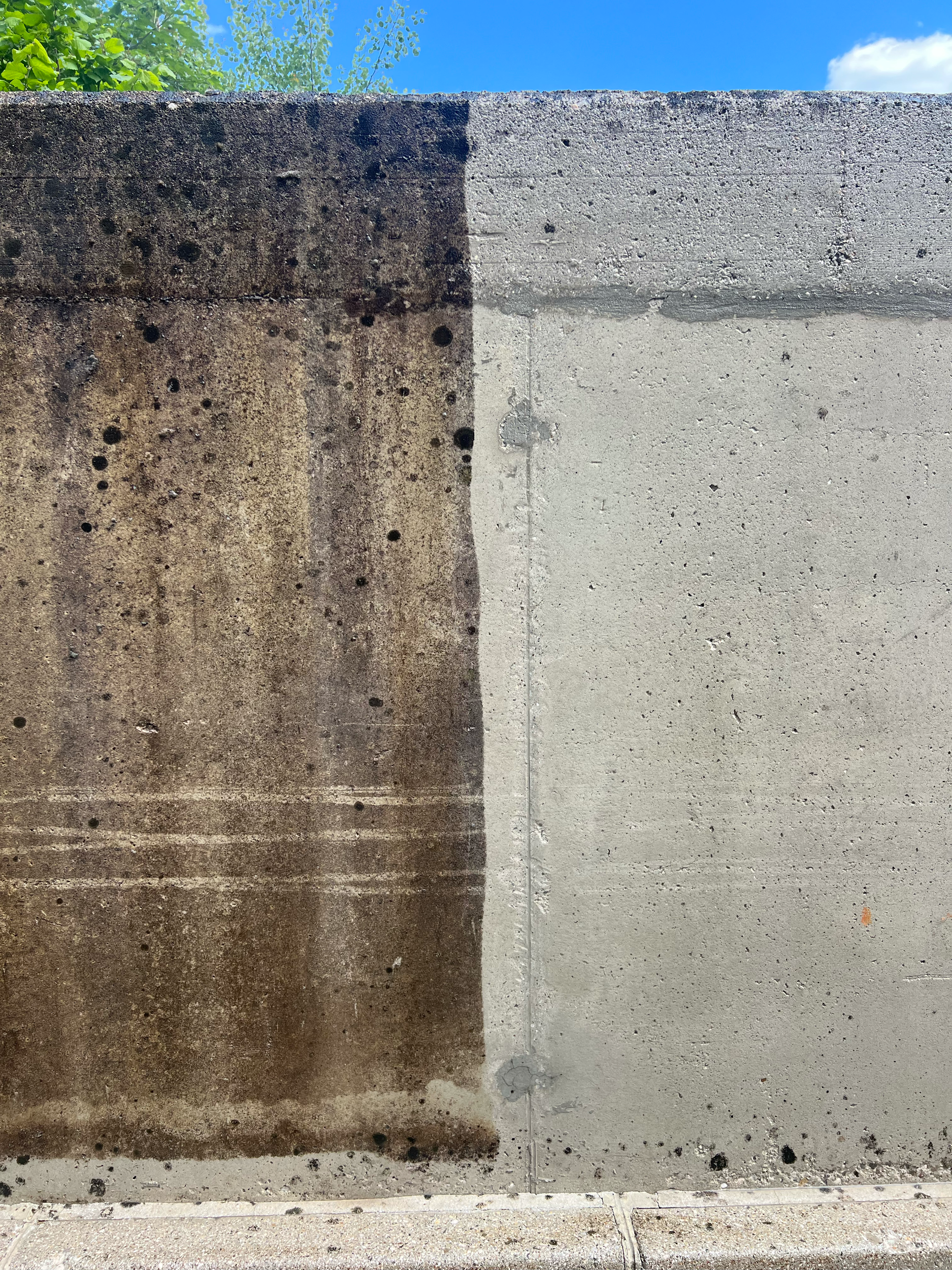 Comparison of four concrete wall surfaces, from left to right: weathered dark brown with spots, weathered light brown with spots, weathered gray, and new light gray with smooth surface.