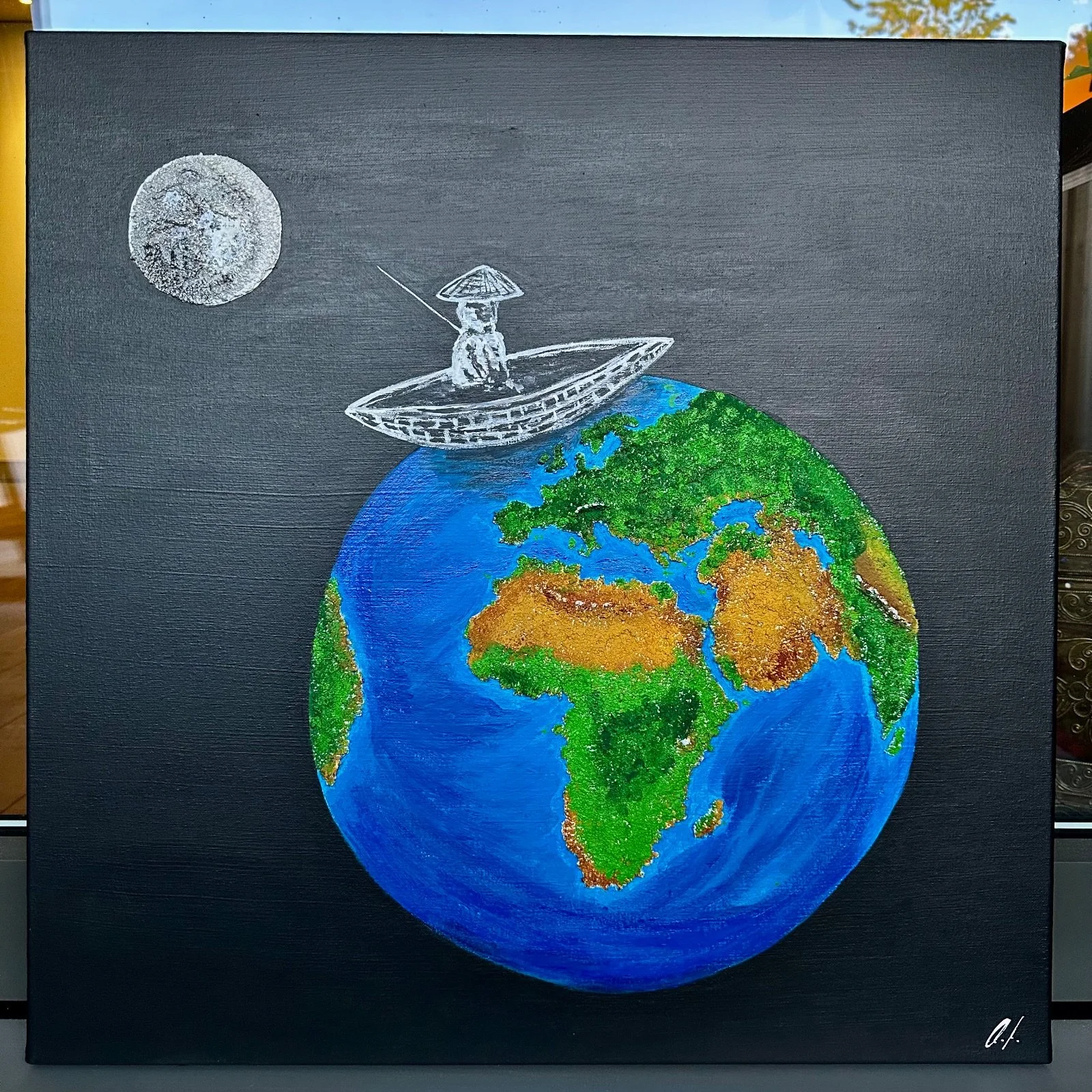 Eine kreative Darstellung der Erde mit einer kleinen Figur in einem Boot, die auf der Erde sitzt, und einem Vollmond im Himmel.