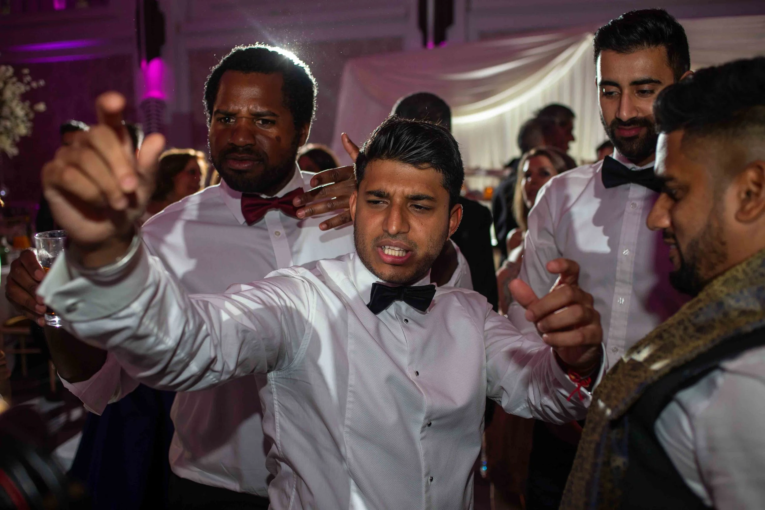 Group of men in formal attire dancing together at a celebration event.