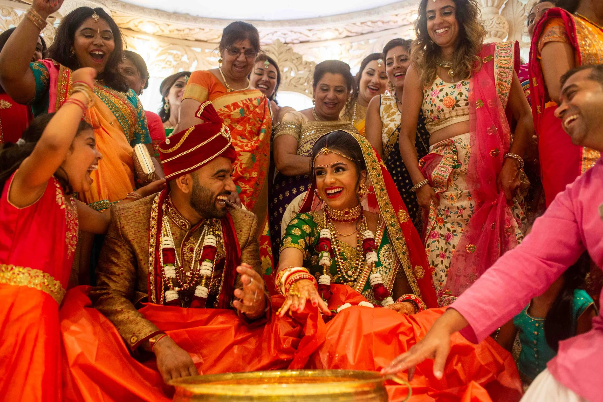 Indian wedding ceremony with bride and groom dressed in traditional attire, surrounded by joyful family and friends.