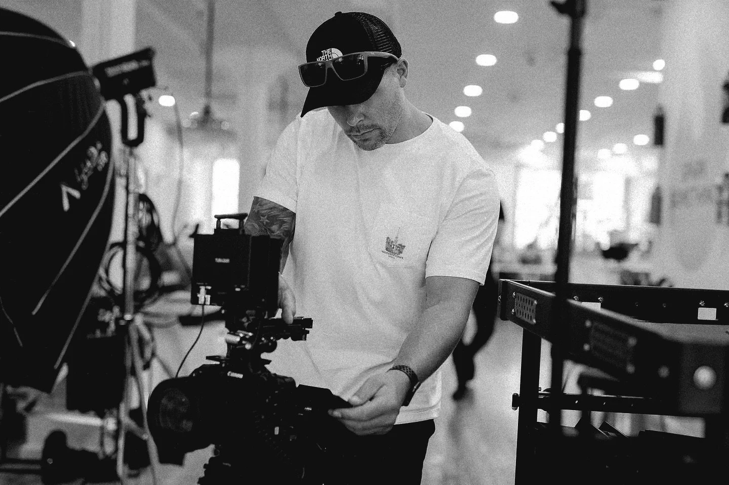 Person in a white shirt and cap using a camera in a studio.