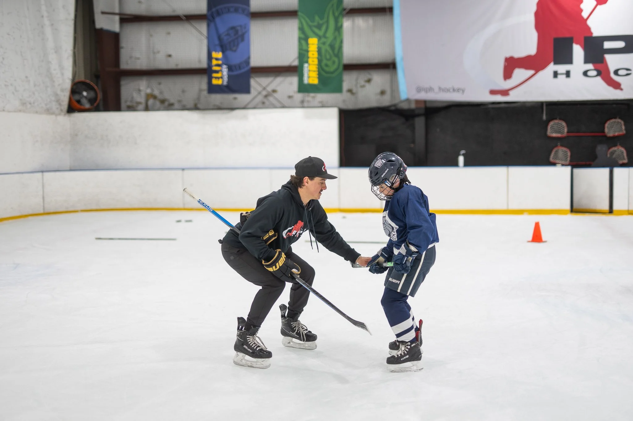 Hockey coach instructing a young player on the ice.