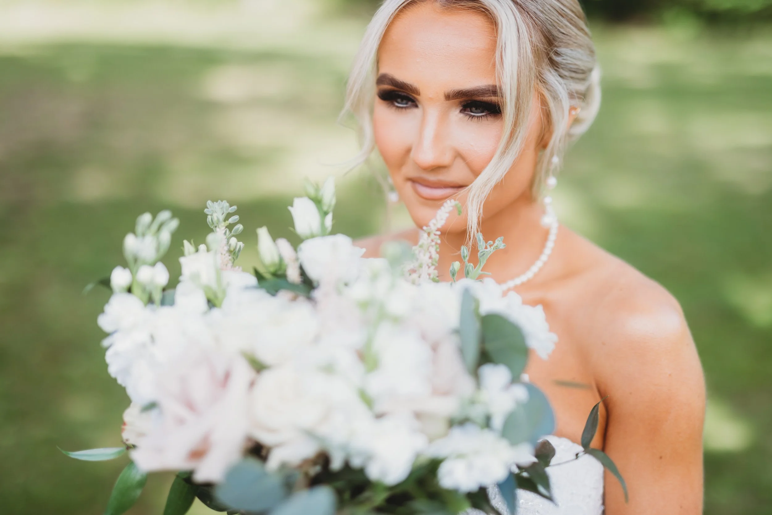 Bride holding white flower bouquet, outdoors, close-up