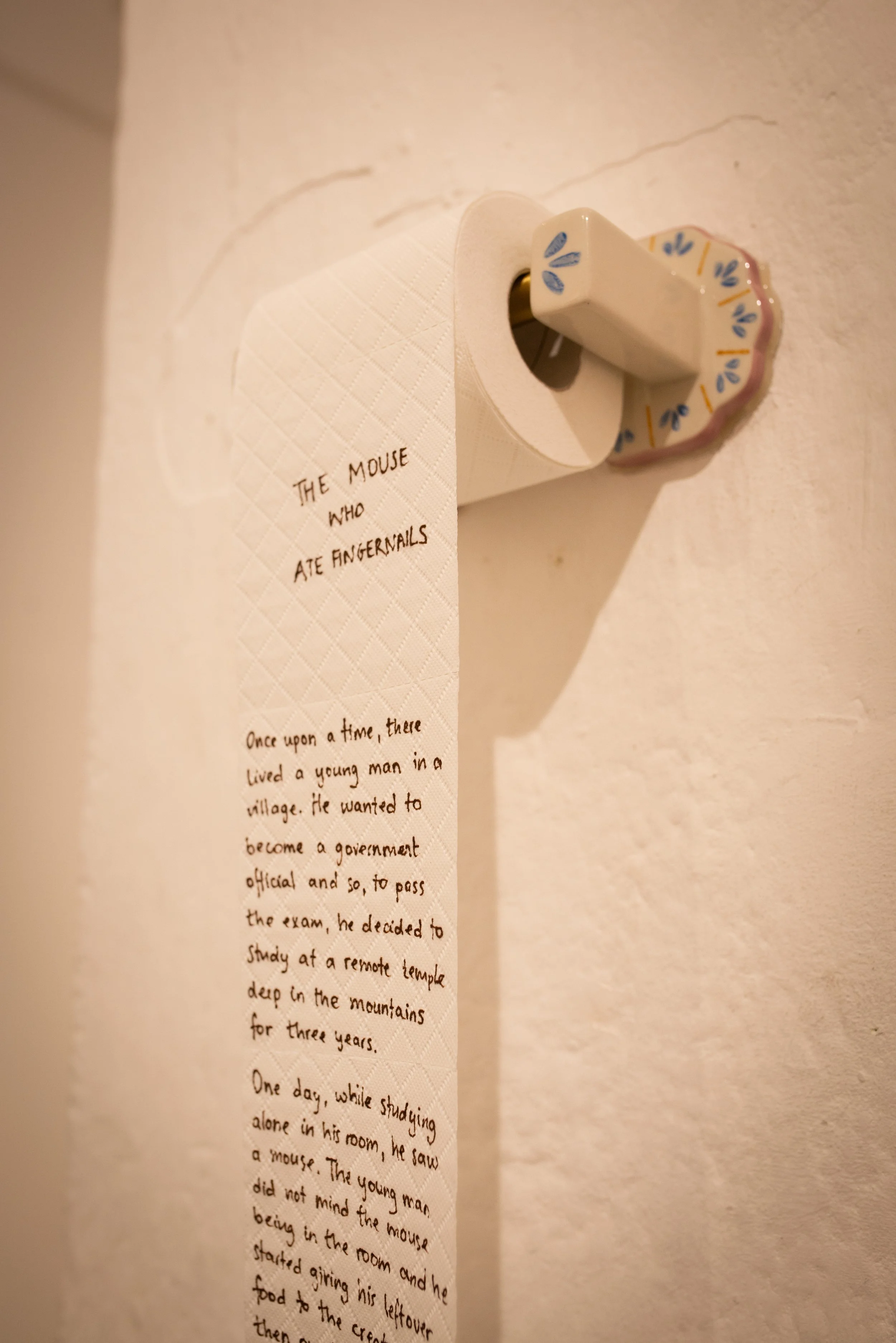 The Mouse Who Ate Fingernails, 2023. Toilet paper, ceramic toilet roll holder, ink — 150 x 15 x 10 cm