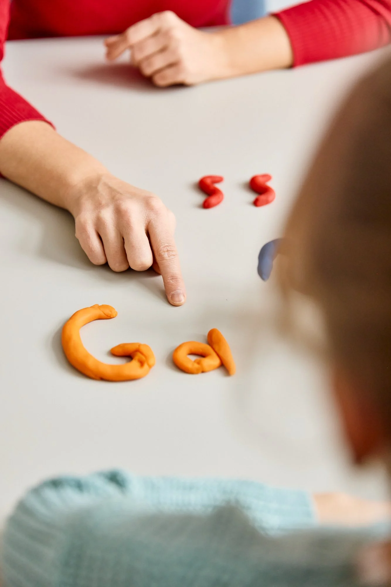 Menschen, die am Tisch sitzen, diskutieren über Puzzlespiele, bei denen Buchstaben aus Knetmasse geformt sind.