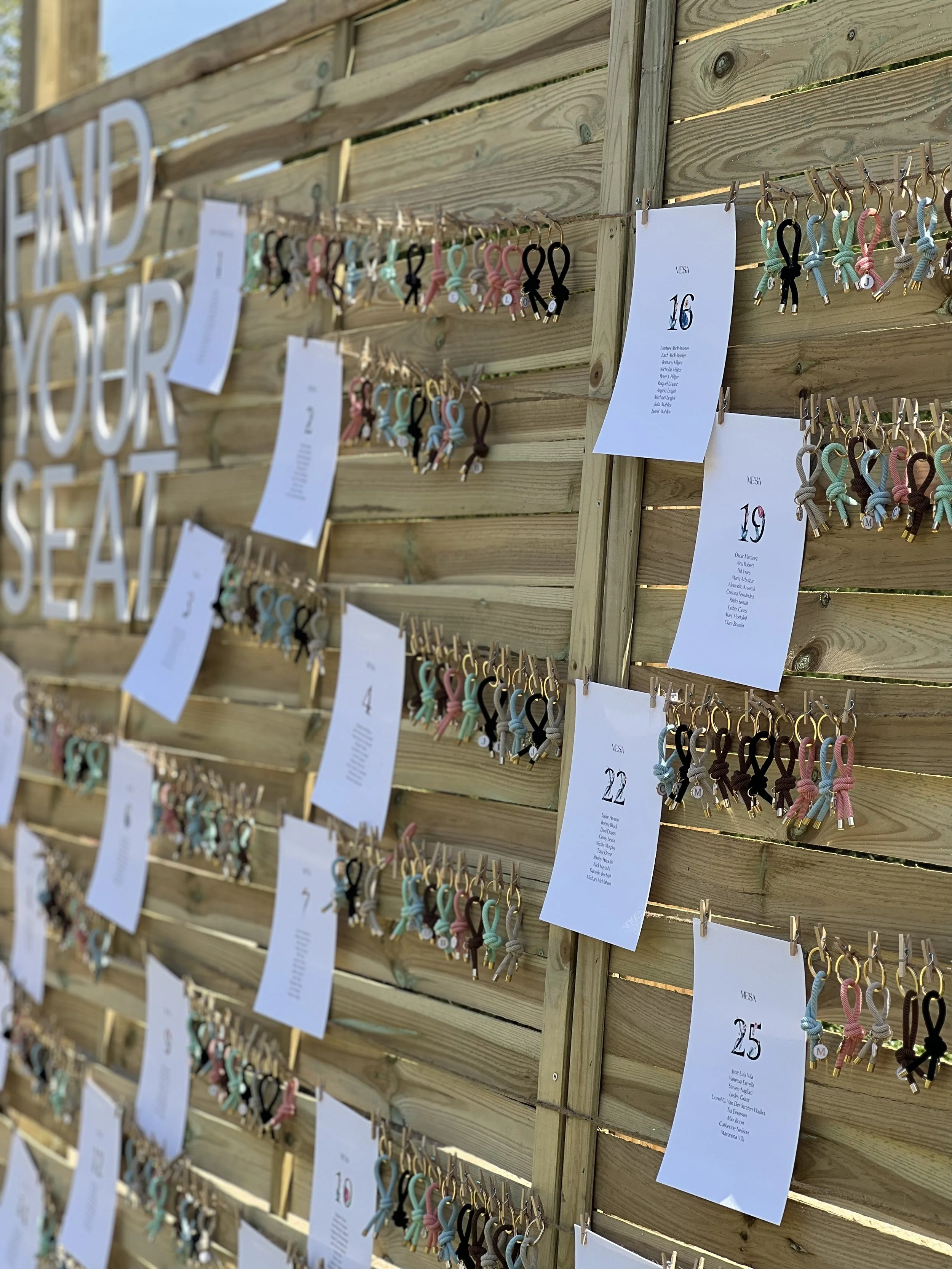Puente de madera con listas y pulseras de cuerda en exhibición, con letras grandes que dicen 'END YOUR SEAT.'