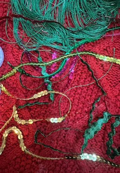 Various tangled beads and threads on a red textured surface.