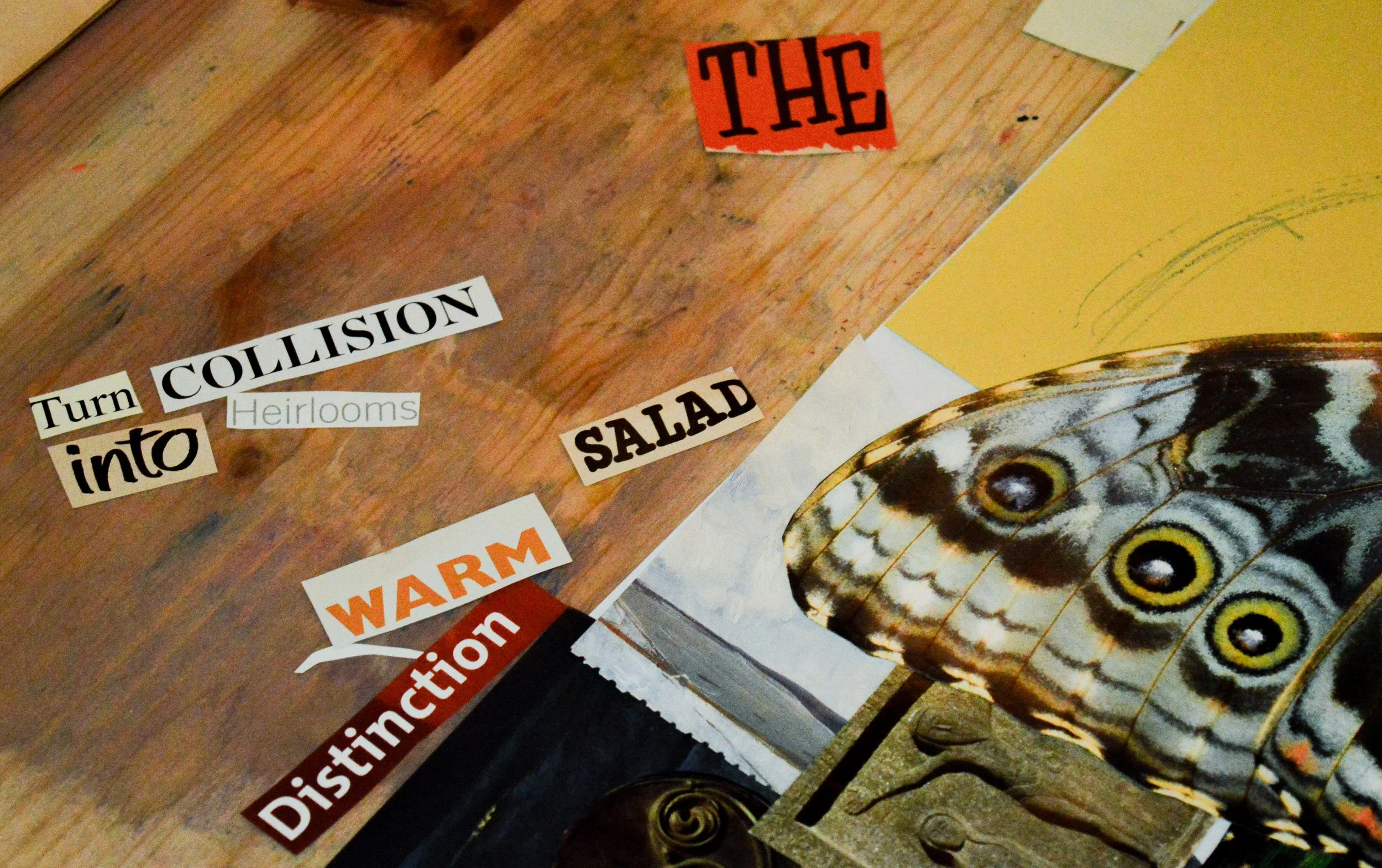 Close-up of a wooden surface with cut-out words and phrases like 'THE,' 'COLLISION,' 'into,' 'Herlooms,' and 'SALE,' along with a large butterfly illustration and part of a circular artwork.