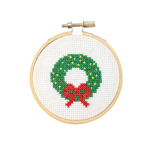 Cross-stitch embroidery of a Christmas wreath with a red bow in a wooden hoop.