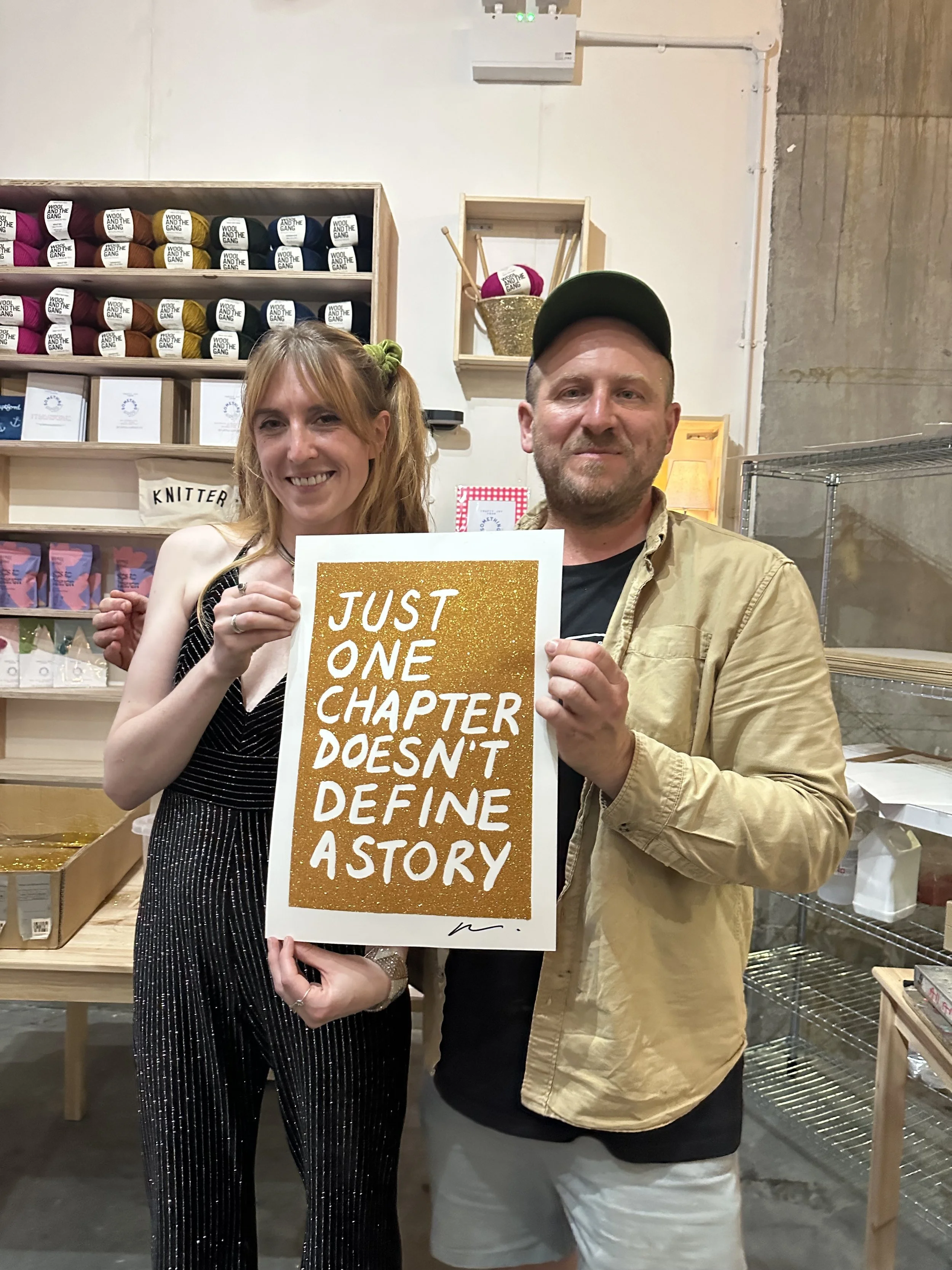 A3 gold glitter screenprint by Adam Bridgland reading “Just One Chapter Doesn’t Define a Story”