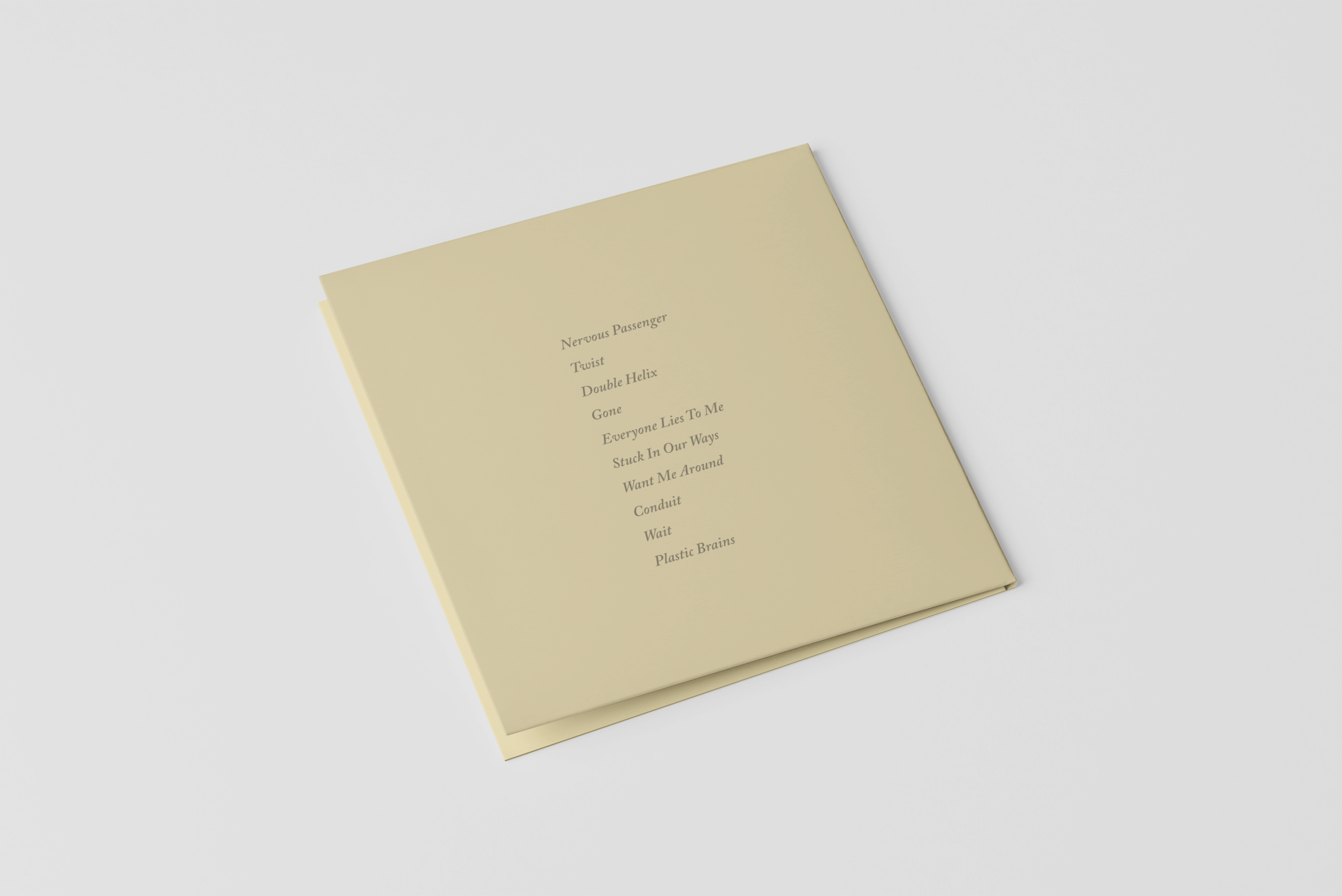 A beige paper booklet with a list of song titles printed in the center, including 'Nervous Passenger,' 'Twist,' 'Double Helix,' 'Gone,' 'Everyone Lies To Me,' 'Stuck In Our Ways,' 'Want Me Around,' 'Conduit,' 'Wait,' and 'Plastic Brains.' The booklet is slightly open and rests on a white surface.