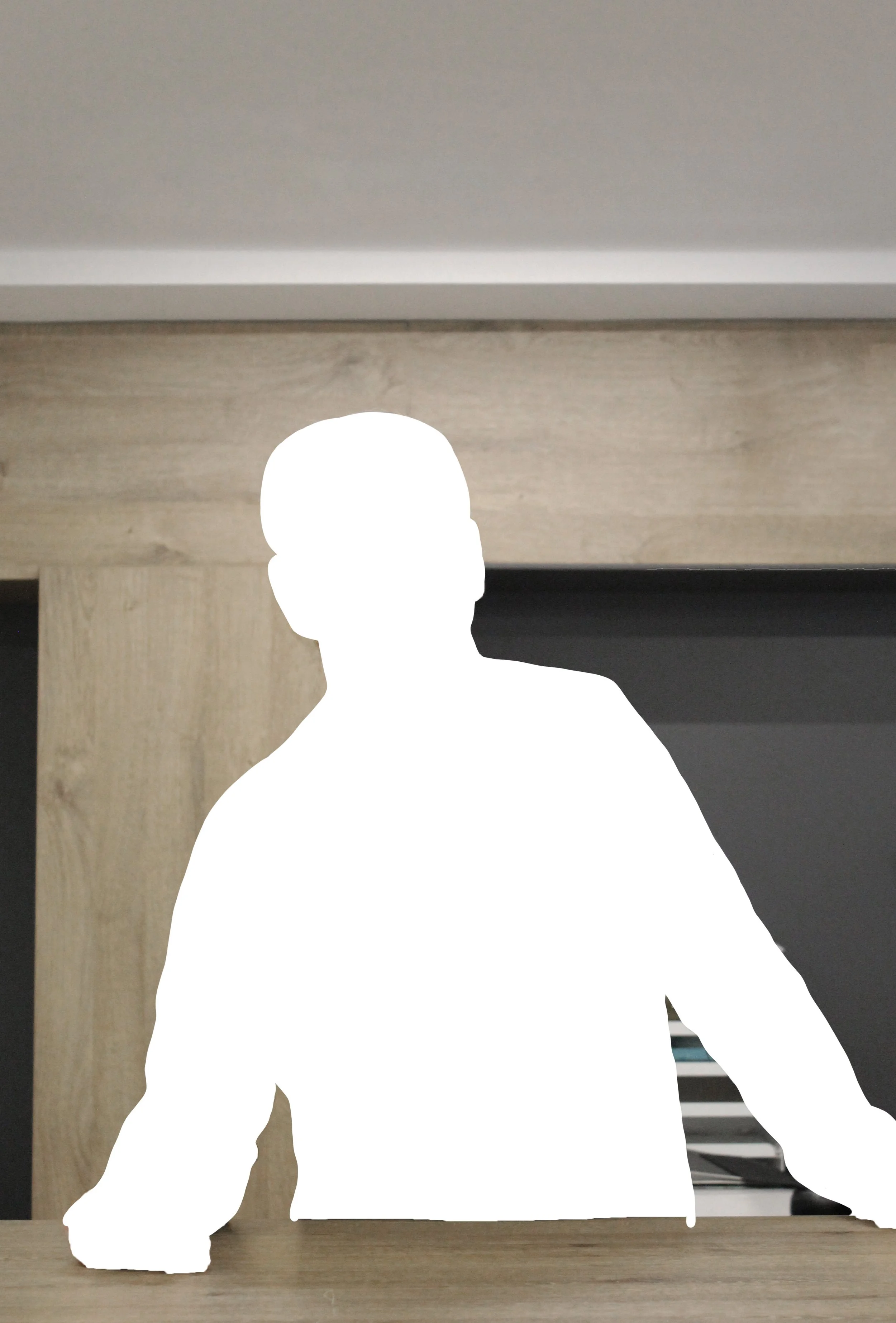 Silhouette einer Person hinter einem Holzschreibtisch in einem modernen Raum.