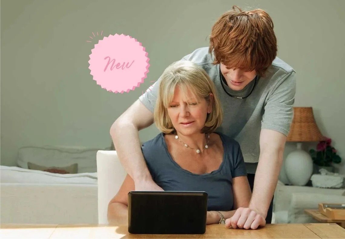 A young man and an elderly woman are looking at a tablet together in a cozy living room, with the woman sitting at the table and the man leaning over her shoulder. There is a pink badge with the word 'New' on the left side.
