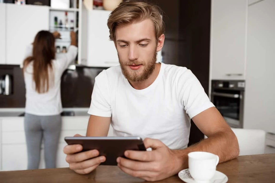 man-looking-tablet-girlfriend-kitchen.jpg