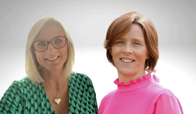 Two women smiling against a light grey background, one with glasses and a green patterned shirt, and the other in a pink top.