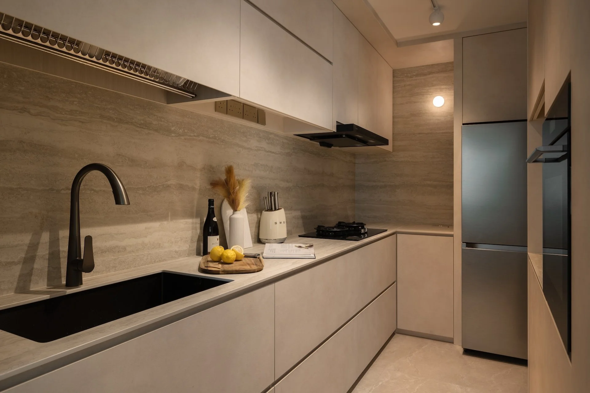 Modern kitchen with beige cabinetry, black sink, lemon fruits, and kitchen utensils on the countertop.