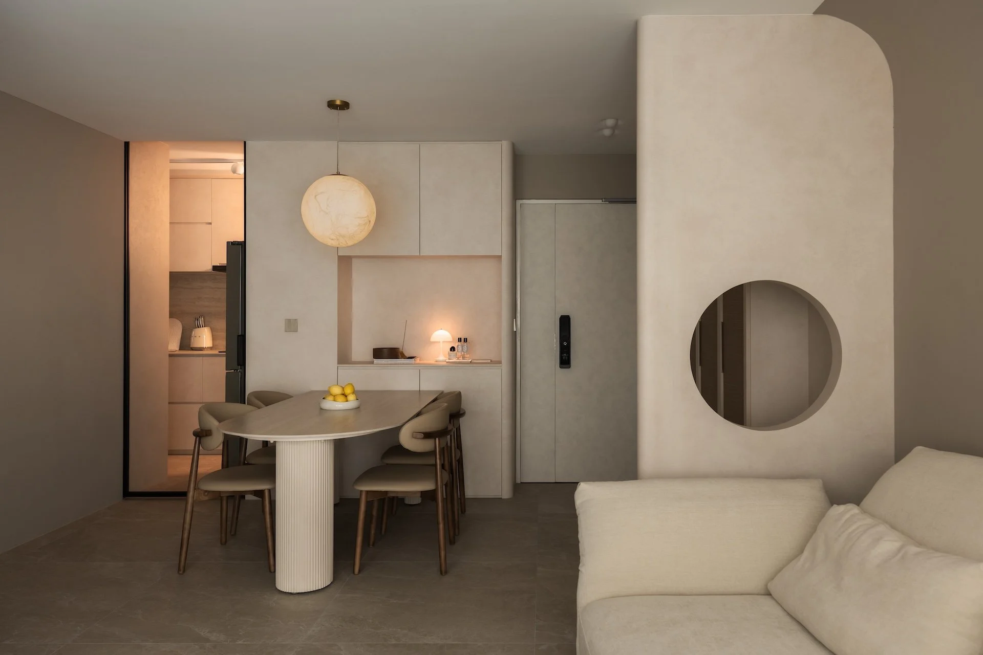 Modern minimalist living and dining area with a round dining table, beige chairs, a white sofa, neutral wall tones, a circular mirror, and decor lighting.