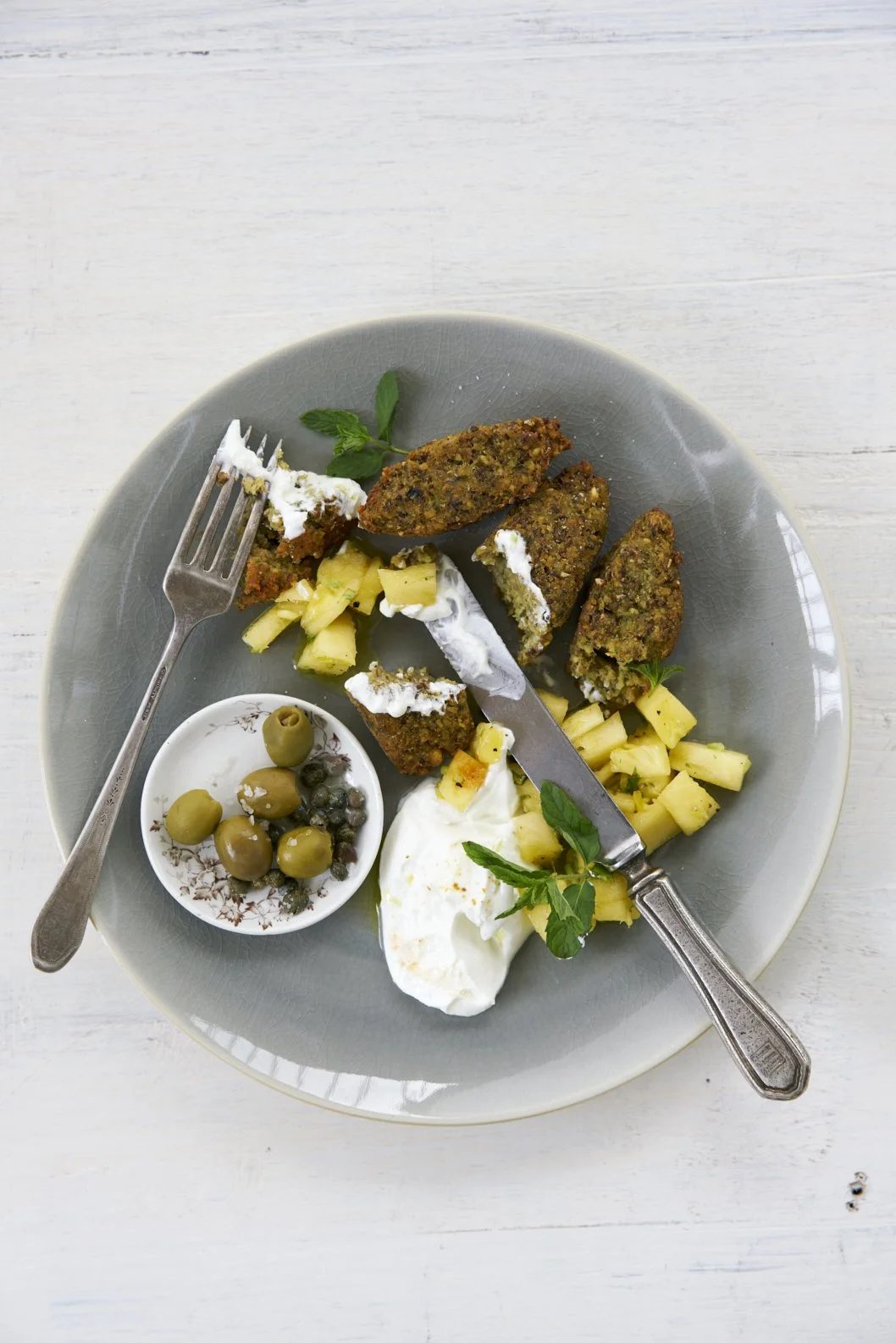 Brown fritters with olives in a gray plate.