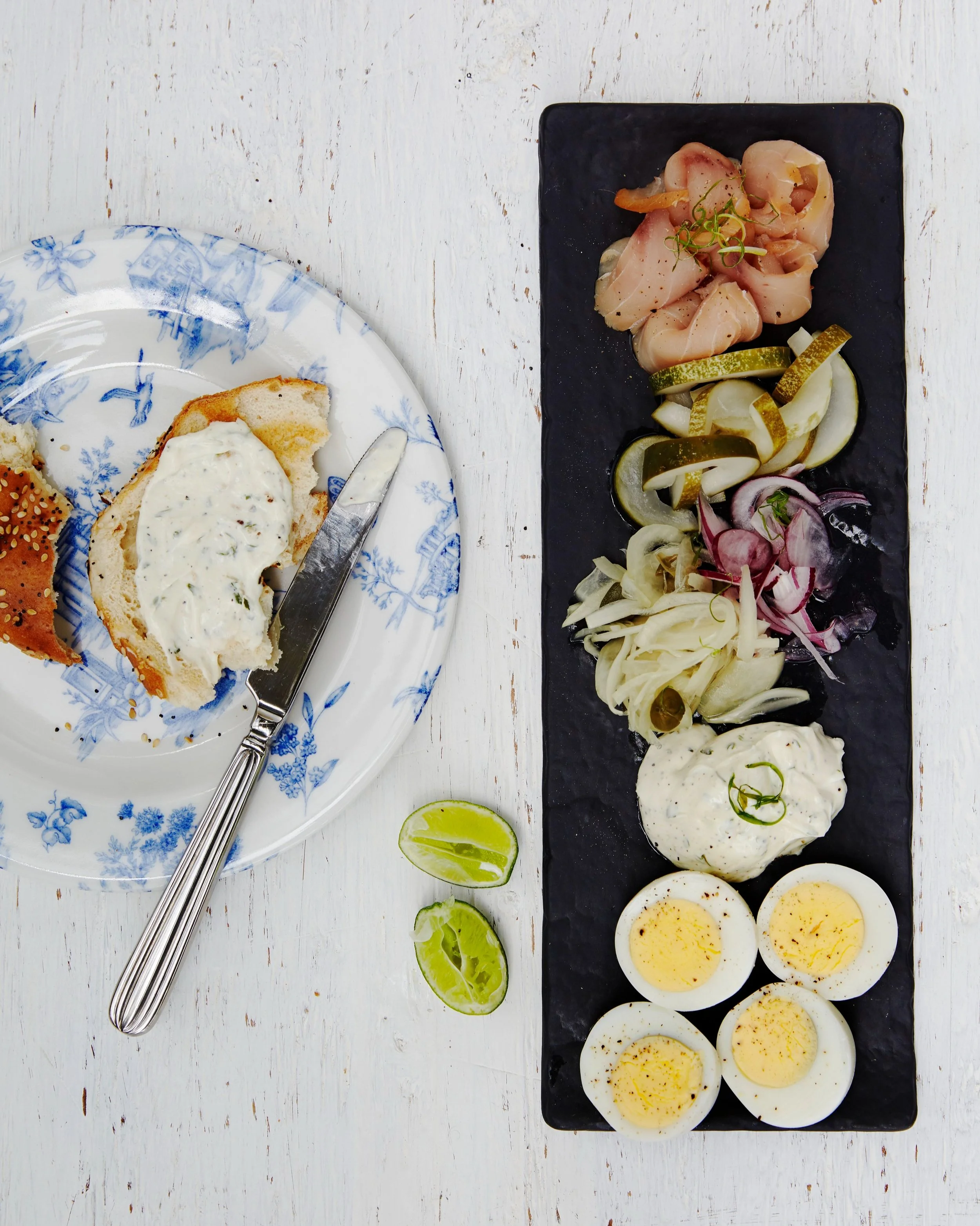Eggs, smoked salmon, pickles, and other ingredients on a black serving tray.
