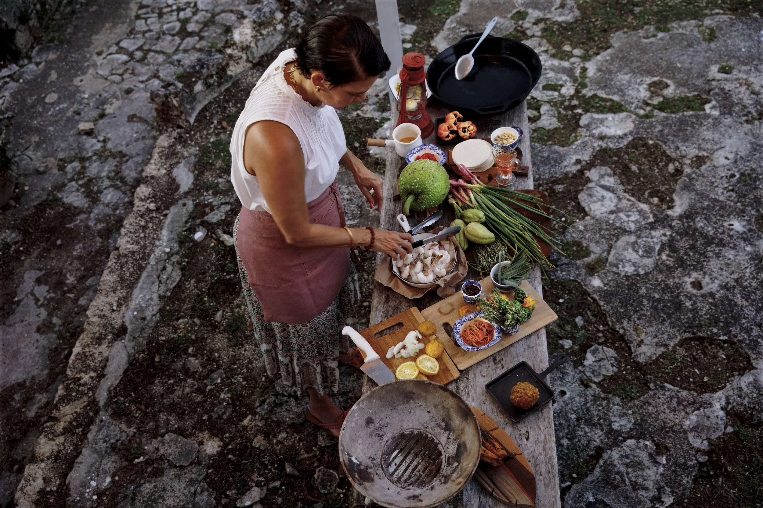 A women preparing food on an outdoor table.