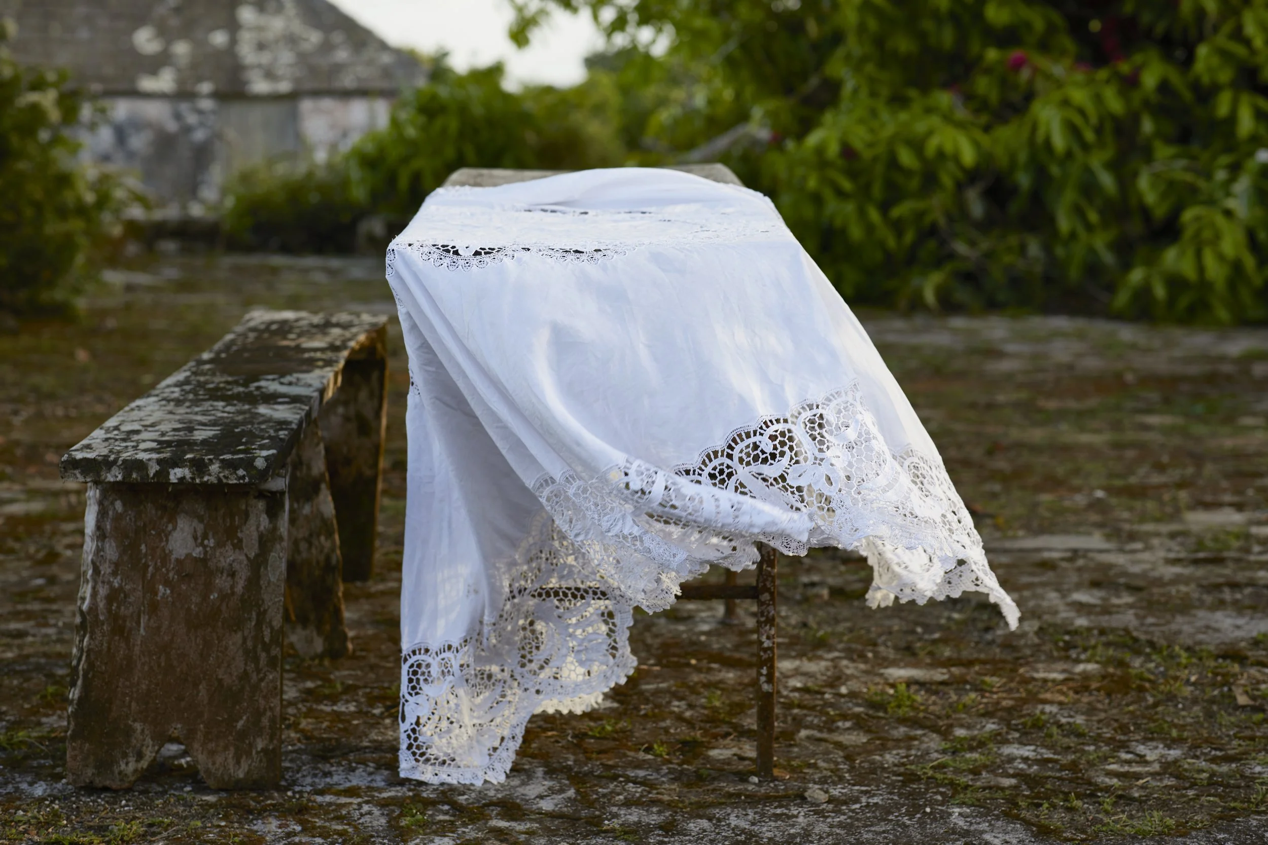 An outdoor rectangular table with a white tablecloth on top.