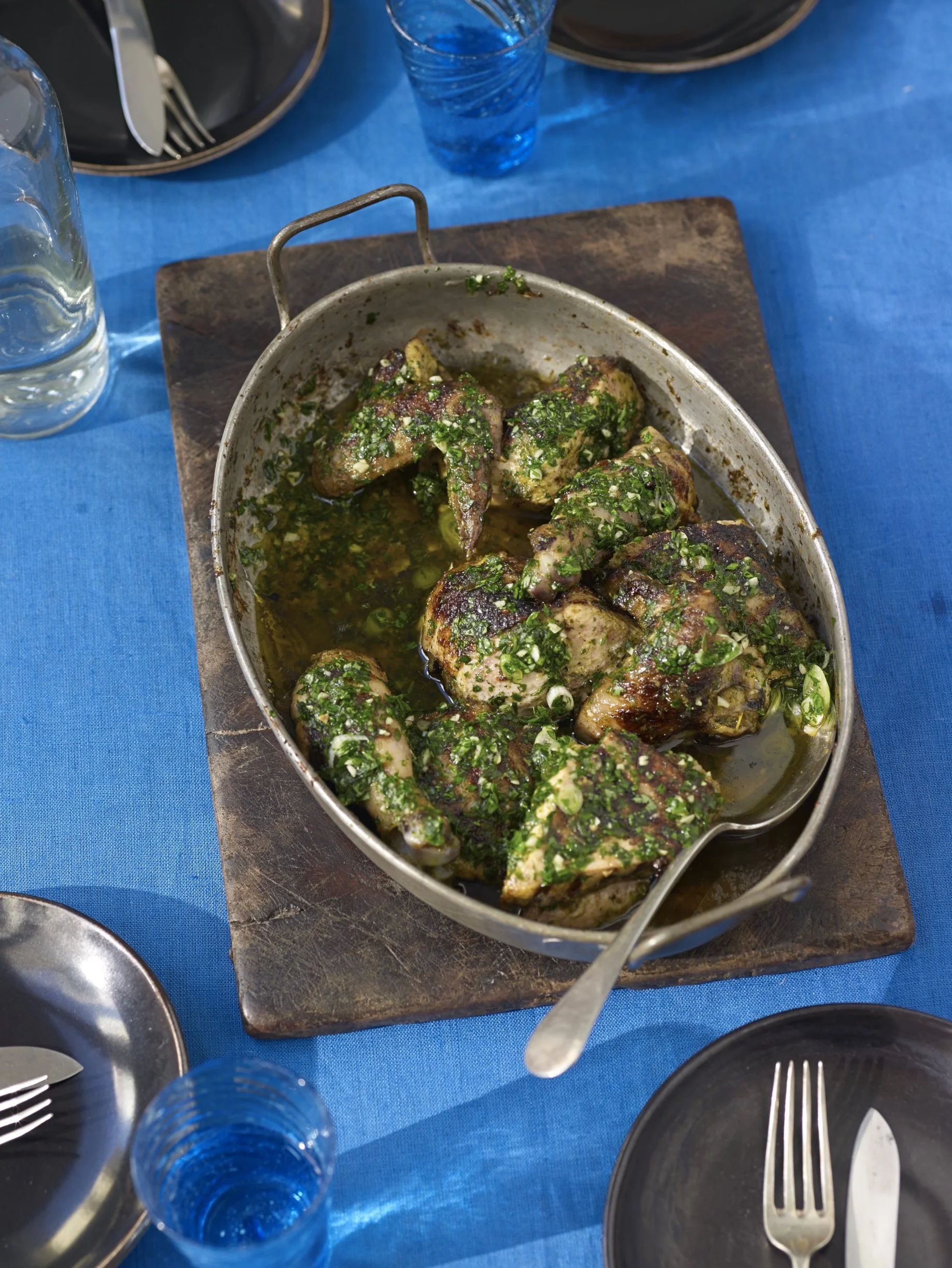 A tray with cooked chicken and green herbs.