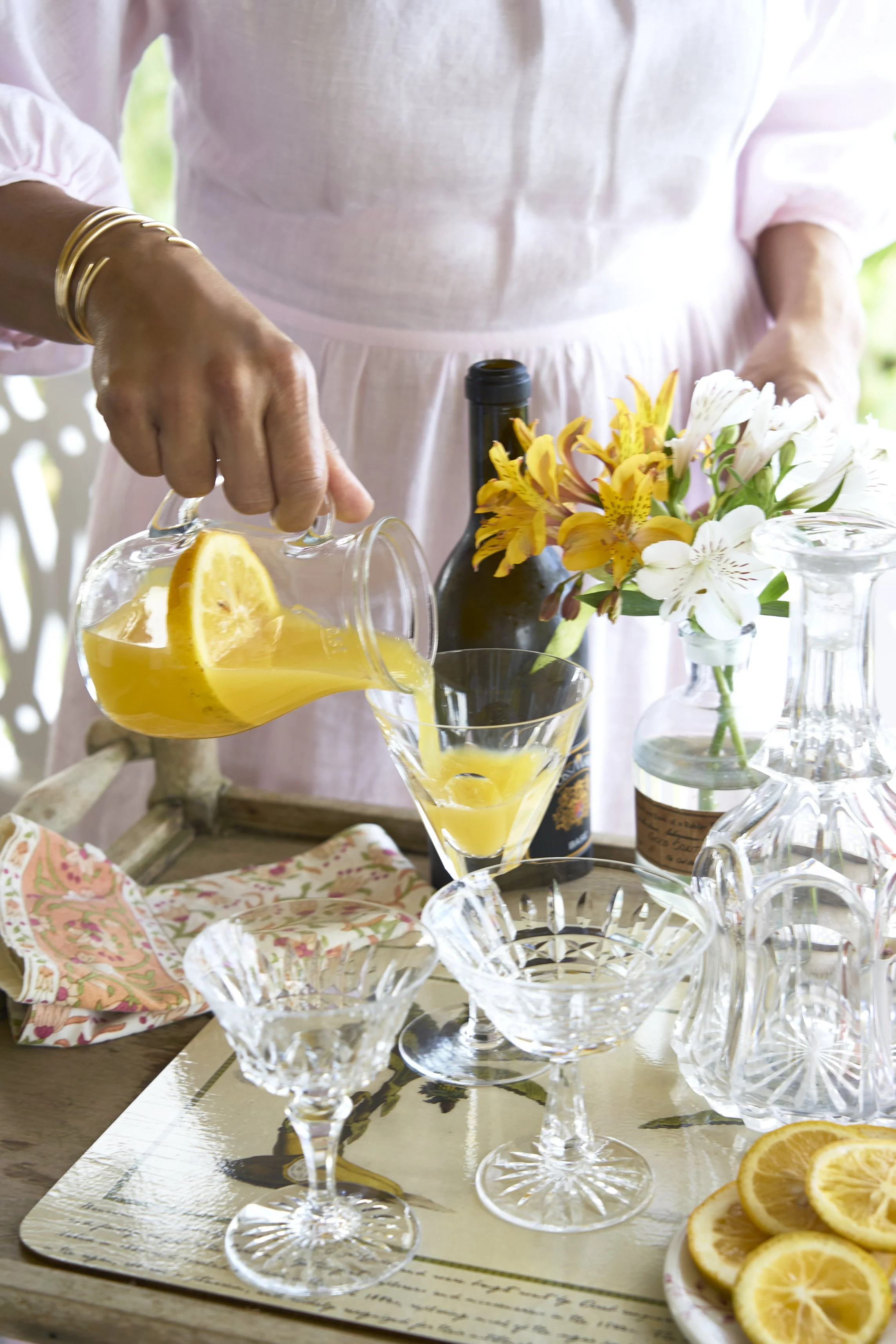A pitcher with an orange cocktail being poured in a glass.