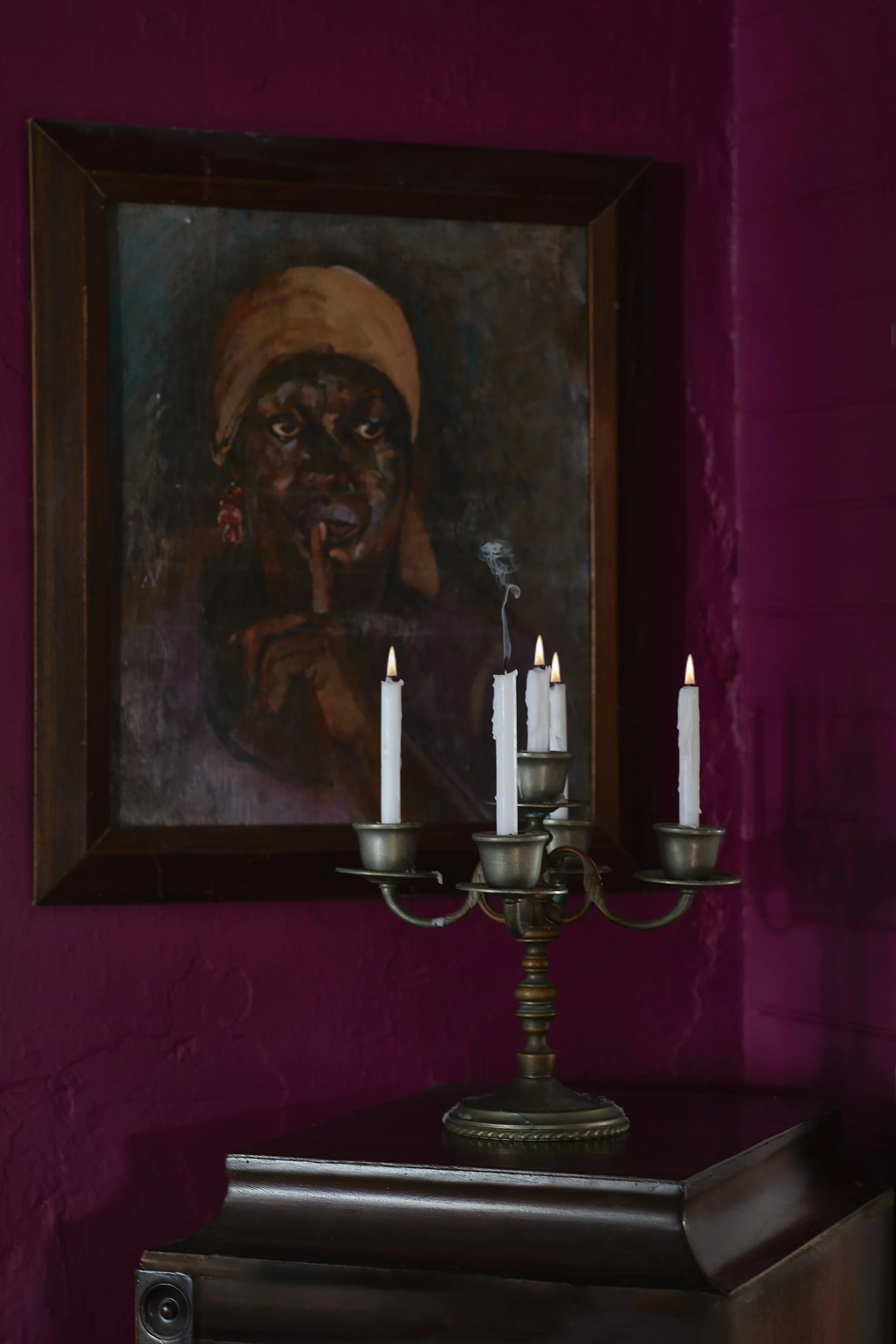 Candles with a painting on a wall.