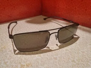 Pair of sunglasses with tinted lenses on a white textured surface against a red wall