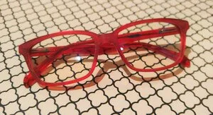 Red eyeglasses resting on a patterned surface.