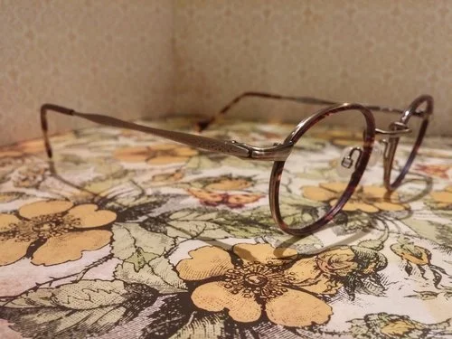 A pair of eyeglasses placed on a floral tablecloth.