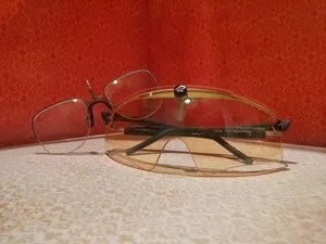 A pair of glasses and a pair of sunglasses on a surface with a red background.