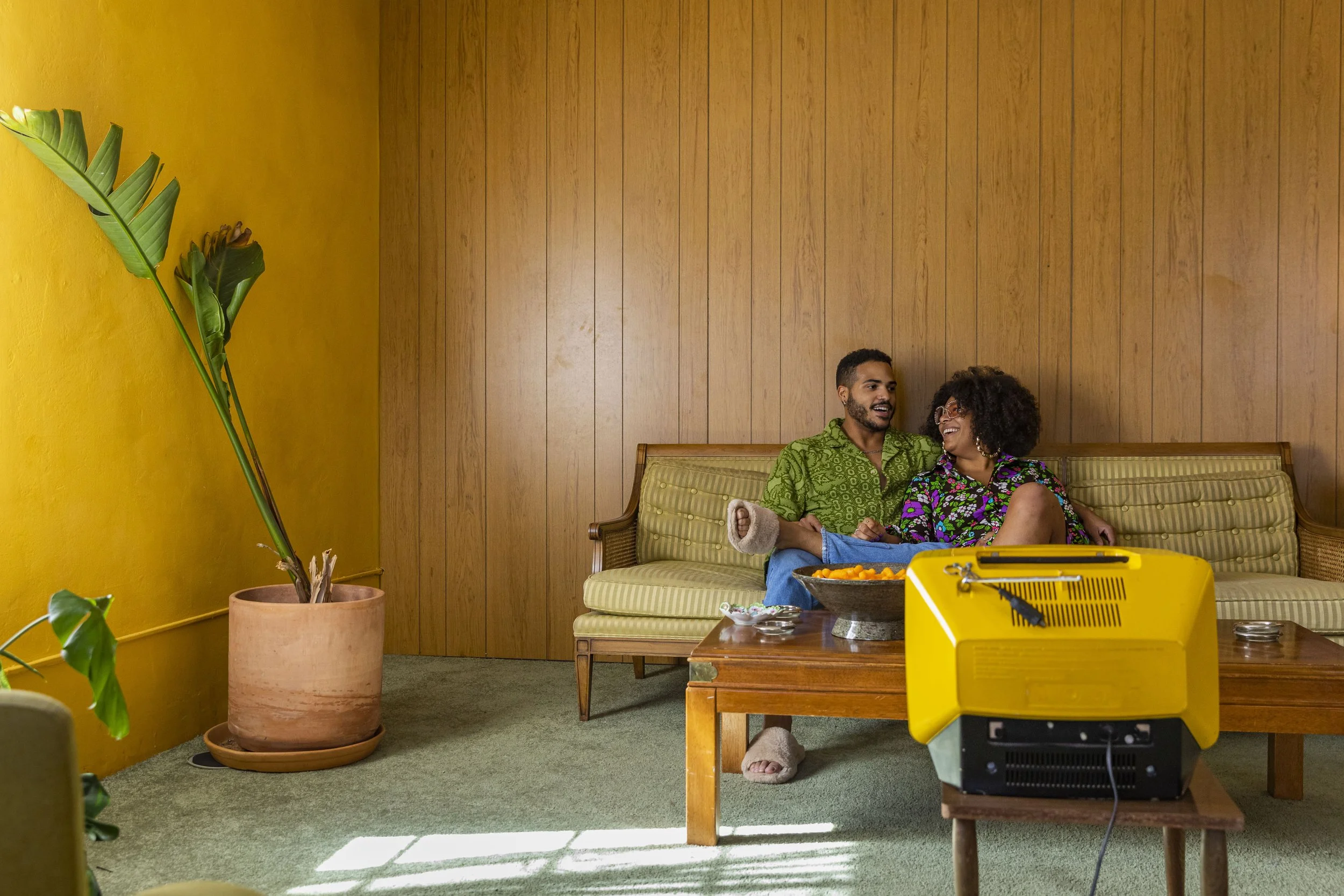 リビング ル⁠ームで一緒にテレビを見ているアフリカ系アメリカ人のカ⁠ップル