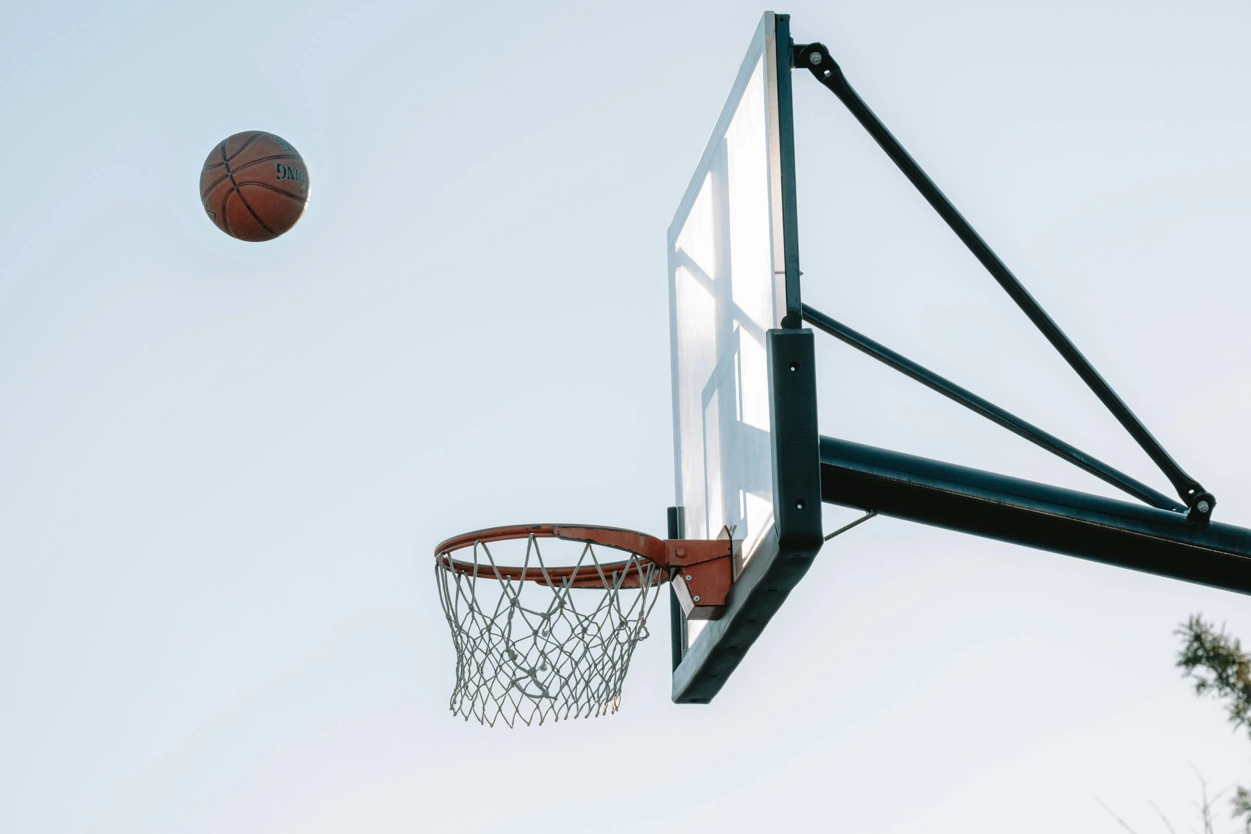 Small red basketball hoop mounted on a textured concrete wall, casting a shadow.