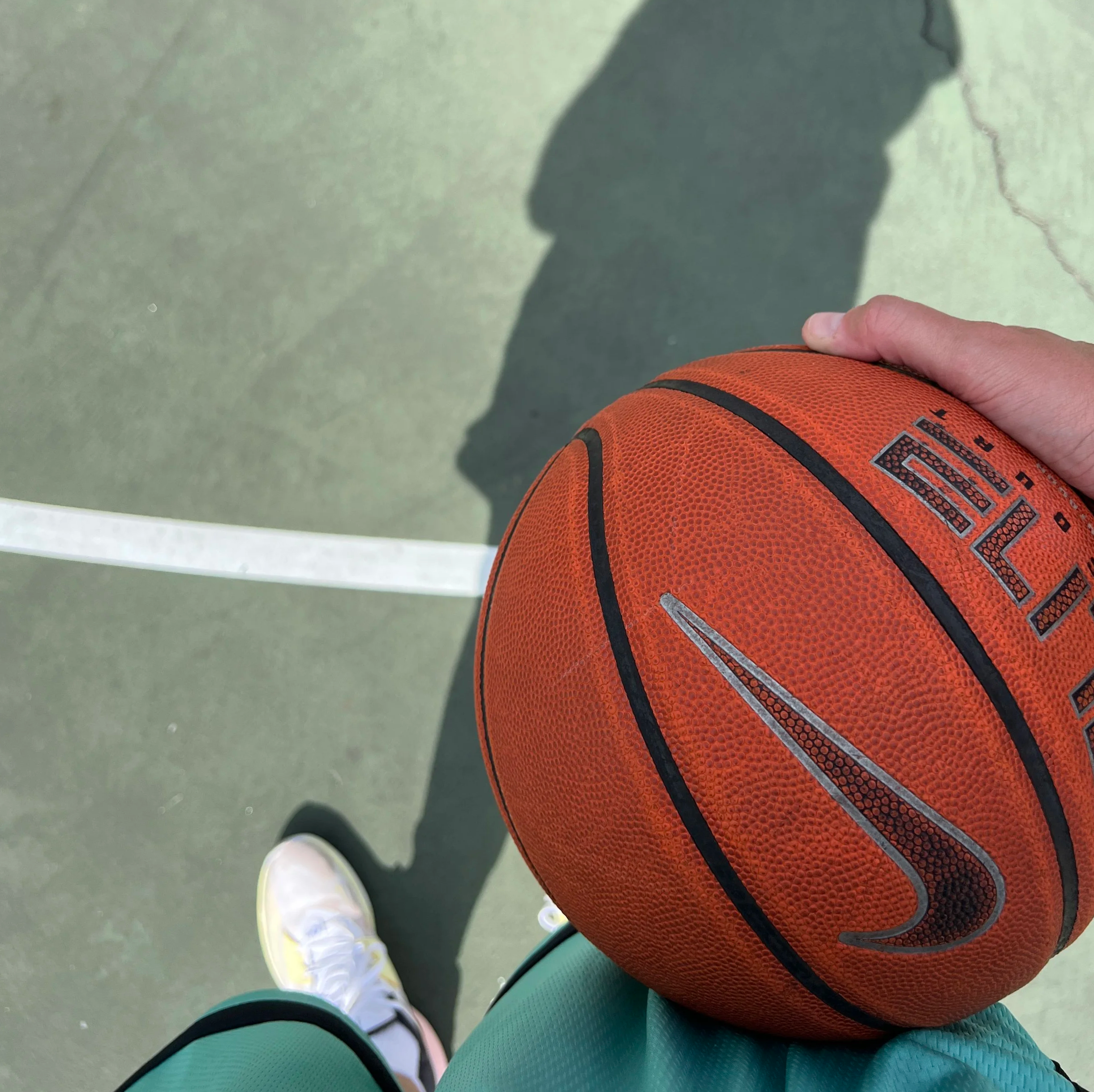 basketball player standing holding a ball on basketball court with shadow