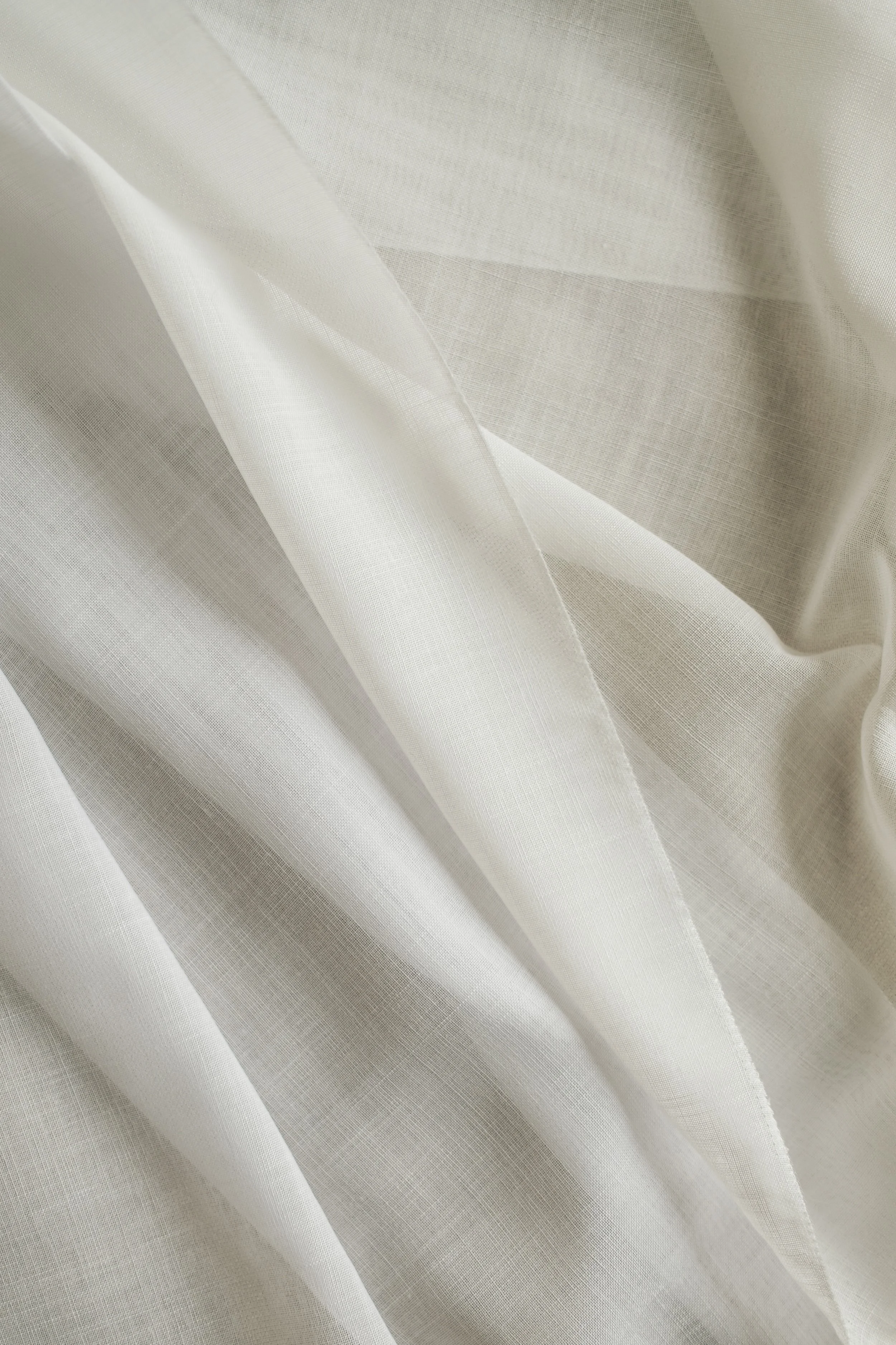 Close-up of white or cream-colored fabric with a smooth and textured surface, showing folds and seams.