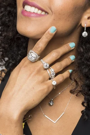 Model wearing jewelry before retouching, showing natural skin textures and blue nail polish