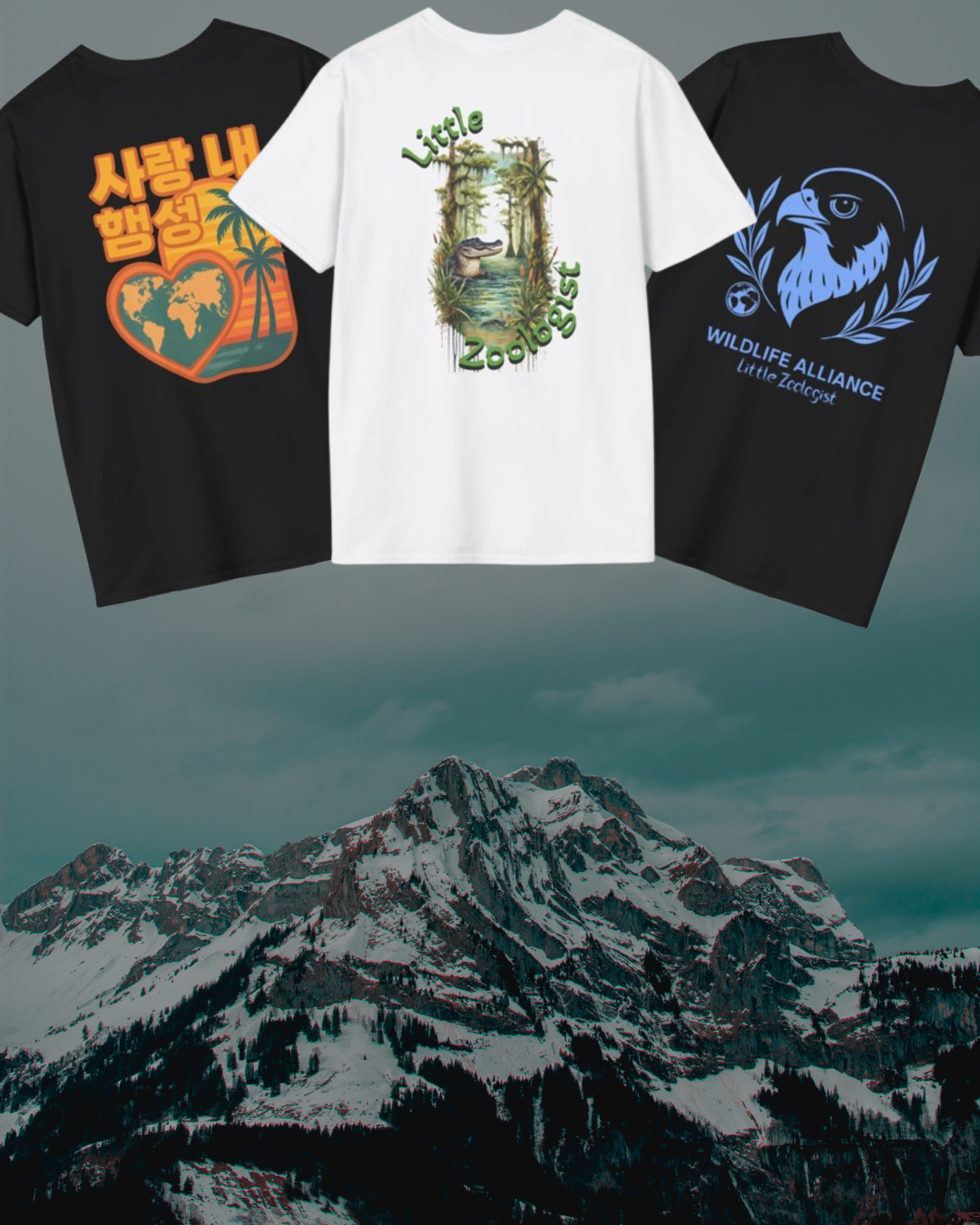 Three t-shirts hanging in front of a mountain landscape with snow-covered peaks. The left black t-shirt has orange and yellow graphics with Korean text, a globe, and a palm tree. The center white t-shirt has a jungle scene with a crocodile and the text 'Little Zoologist.' The right black t-shirt has a blue graphic of a bird's head, laurel wreath, and the text 'Wildlife Alliance Little Zoologist'.
